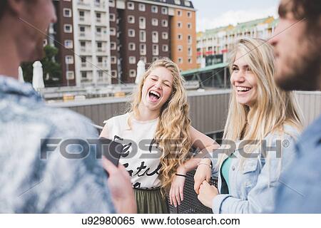 Stock Photography - Friends standing and chatting beside rail. Fotosearch