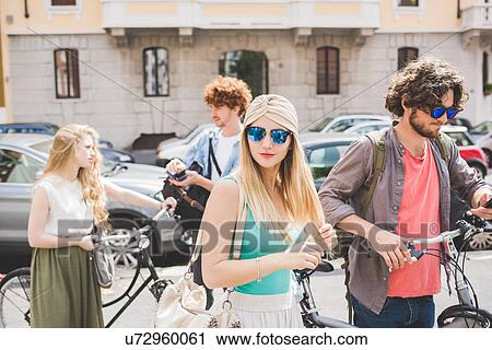 Stock Image - Friends walking along with push bikes. Fotosearch