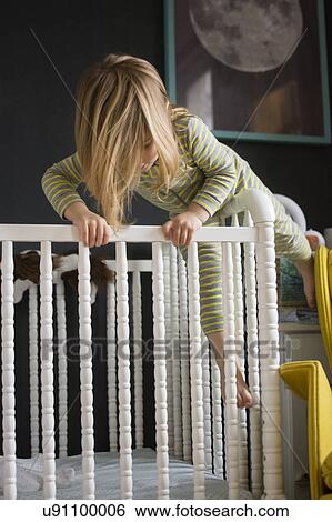 Stock Photograph - Girl (2-3) climbing on crib. Fotosearch
