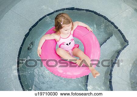 Stock Image - Girl (2-3) on inflatable ring in pool. Fotosearch
