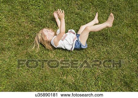 Stock Image - Girl (2-3) rolling on grass. Fotosearch