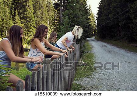 Girl and adult female friends climbing fence in forest View Large Photo Image Stock Photo - Girl and adult female friends climbing fence in forest. Fotosearch