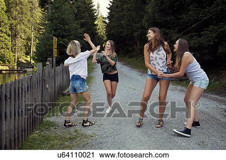 Stock Image - Girl and adult female friends high fiving on forest track. Fotosearch