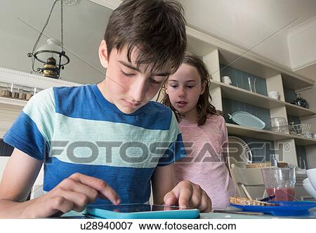 Stock Photo - Girl and boy using digital tablet. Fotosearch