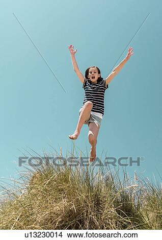 Girl in mid air jumping over dune View Large Photo Image Picture - Girl in mid air jumping over dune. Fotosearch