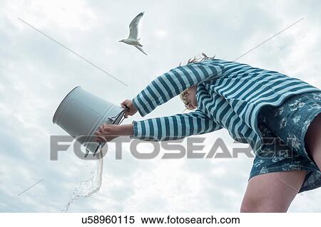 Girl pouring water from bucket View Large Photo Image Stock Photography - Girl pouring water from bucket. Fotosearch