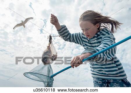 Stock Photo - Girl pulling fish from fishing net. Fotosearch