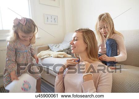 Girl putting necklace onto mother in living room View Large Photo Image Stock Image - Girl putting necklace onto mother in living room. Fotosearch