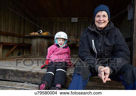 Girl wearing skiing helmet sitting on barn step with grandmother, Gavle, Sweden View Large Photo Image Picture - Girl wearing skiing helmet sitting on barn step with grandmother, Gavle, Sweden. Fotosearch
