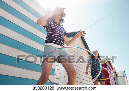 Stock Photo - Girls hoola hooping by beach huts, Southwold, Suffolk, UK. Fotosearch