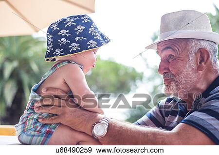 Stock Photo - Grandfather making faces at baby boy. Fotosearch