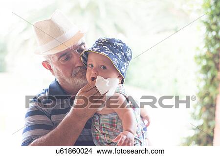 Picture - Grandfather wiping baby boy's chin with handkerchief. Fotosearch