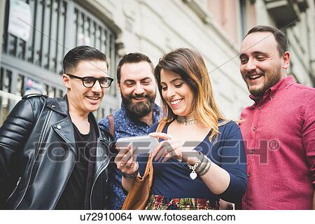 Group of friends looking at message on cellphone View Large Photo Image Picture - Group of friends looking at message on cellphone. Fotosearch