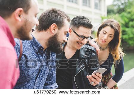 Stock Image - Group of friends looking at message on cellphone. Fotosearch