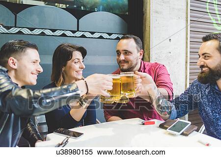 Stock Photography - Group of friends toasting at outdoor cafe. Fotosearch