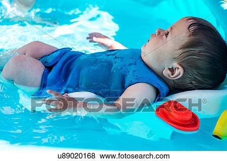 Stock Photo - Happy baby boy playing in inflatable pool on summer day. Fotosearch