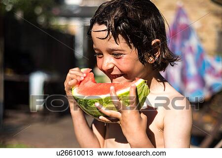 Stock Image - Happy boy eating watermelon on summer day. Fotosearch