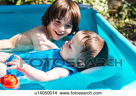 Picture - Happy brothers playing in inflatable pool on summer day. Fotosearch
