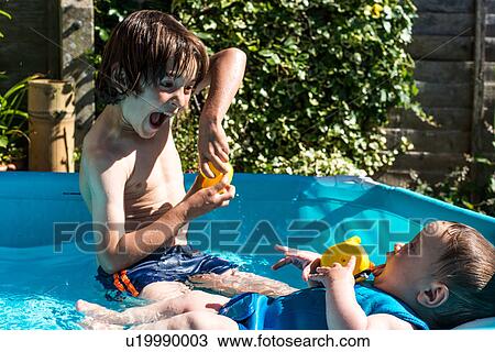 Happy brothers playing in inflatable pool on summer day View Large Photo Image Stock Image - Happy brothers playing in inflatable pool on summer day. Fotosearch