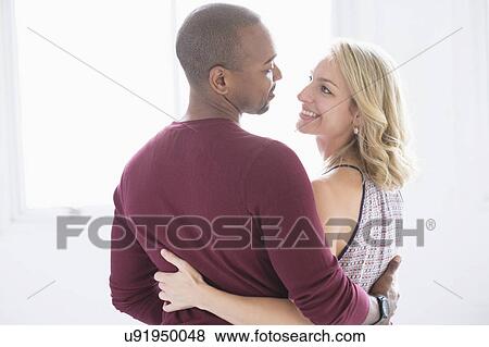 Stock Photo - Happy multi ethnic couple looking at each other. Fotosearch