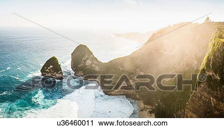 Stock Image - High angle sunlit view of rock formation and sea, Peluwang, South Coast, Nusa Penida, Indonesia. Fotosearch