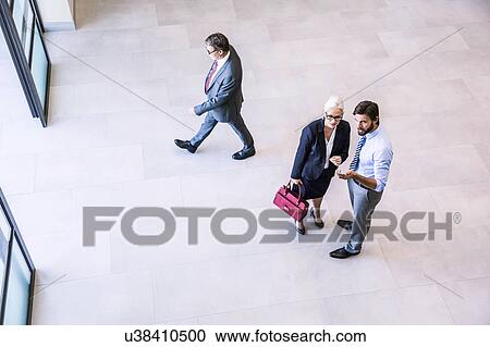 High angle view of two businessman directing businesswoman in office atrium View Large Photo Image Stock Image - High angle view of two businessman directing businesswoman in office atrium. Fotosearch