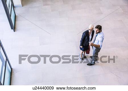 High angle view of two businessman directing businesswoman in office atrium View Large Photo Image Stock Photo - High angle view of two businessman directing businesswoman in office atrium. Fotosearch