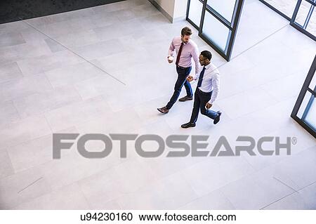 High angle view of two businessmen arriving in office atrium View Large Photo Image Stock Image - High angle view of two businessmen arriving in office atrium. Fotosearch