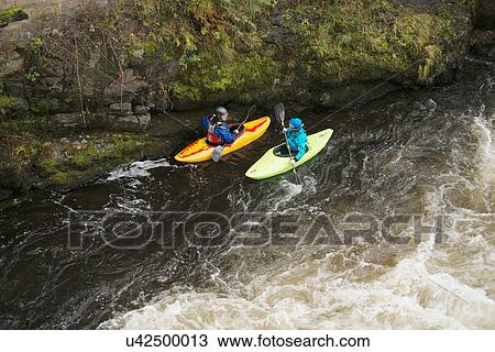 Stock Image - High angle view of two kayakers paddling River Dee rapids, Llangollen, North Wales. Fotosearch
