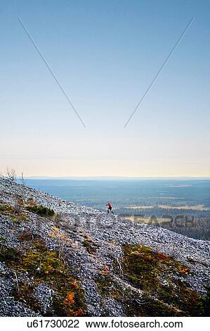 Stock Image - Hiker ascending rocky steep hill, Kesankitunturi, Lapland, Finland. Fotosearch