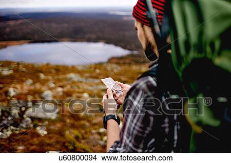 Picture - Hiker checking compass on cliff top, Keimiotunturi, Lapland, Finland. Fotosearch