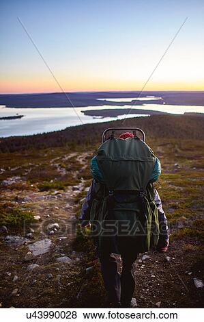 Stock Photo - Hiker enjoying sunset at lake, Keimiotunturi, Lapland, Finland. Fotosearch