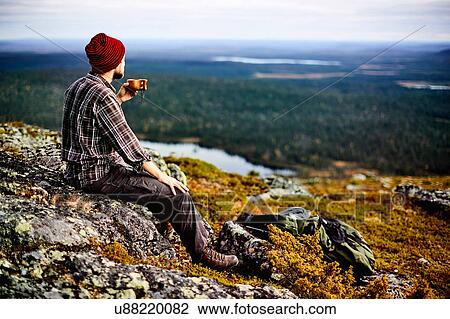 Stock Image - Hiker enjoying view on cliff top, Keimiotunturi, Lapland, Finland. Fotosearch