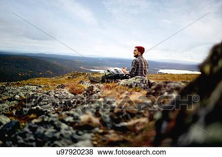 Stock Photo - Hiker enjoying view on cliff top, Keimiotunturi, Lapland, Finland. Fotosearch