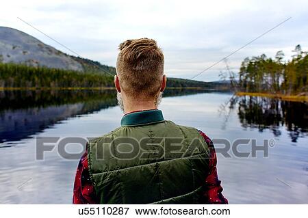 Stock Photo - Hiker looking out at lake, Kesankijarvi, Lapland, Finland. Fotosearch