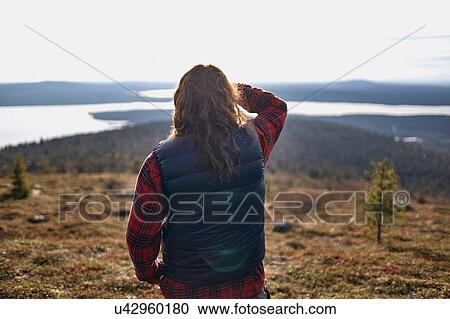 Stock Image - Hiker looking out to lake, Keimiotunturi, Lapland, Finland. Fotosearch