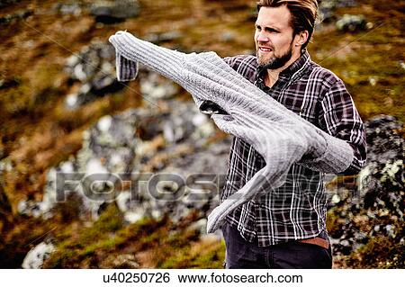 Stock Photograph - Hiker putting on sweater, Keimiotunturi, Lapland, Finland. Fotosearch