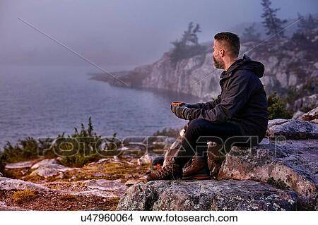 Hiker relaxing with coffee on cliff top, Sarkitunturi, Lapland, Finland View Large Photo Image Picture - Hiker relaxing with coffee on cliff top, Sarkitunturi, Lapland, Finland. Fotosearch