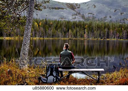 Hiker resting on bench, looking out at lake, Kesankijarvi, Lapland, Finland View Large Photo Image Stock Image - Hiker resting on bench, looking out at lake, Kesankijarvi, Lapland, Finland. Fotosearch