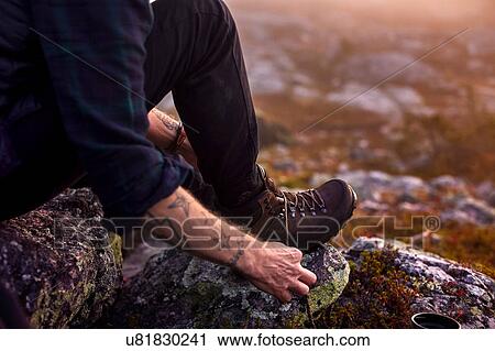 Stock Image - Hiker tying shoelace on rocky field, Sarkitunturi, Lapland, Finland. Fotosearch
