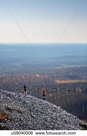 Stock Photo - Hikers enjoying view on rocky steep hill, Kesankitunturi, Lapland, Finland. Fotosearch