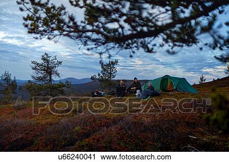 Stock Image - Hikers relaxing in front of tent, Keimiotunturi, Lapland, Finland. Fotosearch