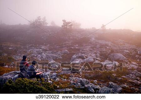 Stock Image - Hikers relaxing with coffee on rocky field, Sarkitunturi, Lapland, Finland. Fotosearch