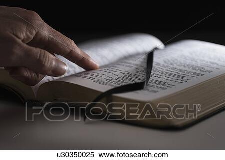 Stock Photography - Human finger on open Bible. Fotosearch