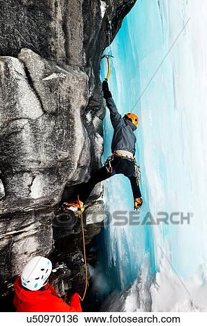 Stock Photograph - Ice climbers climbing on rock face. Fotosearch