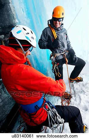 Stock Image - Ice climbers in ice cave preparing climbing equipment. Fotosearch