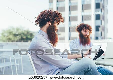 Identical male hipster twins using digital tablet on apartment roof terrace View Large Photo Image Stock Photo - Identical male hipster twins using digital tablet on apartment roof terrace. Fotosearch