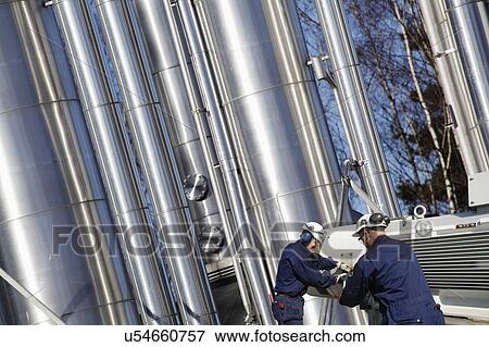 Stock Photo - Industrial workers and oil pipes. Fotosearch