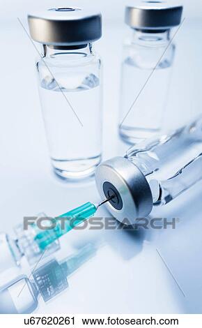 Stock Image - Injectable medications in sealed vials and a disposable plastic medical syringe. Fotosearch