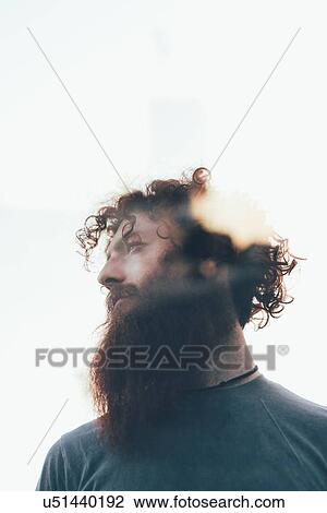 Stock Image - Low angle lens flare portrait of bearded hipster. Fotosearch